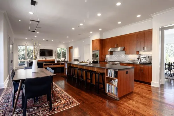 a open kitchen with stainless steel appliances granite countertop a refrigerator a sink dishwasher a stove and a dining table with wooden floor