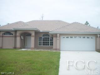 436 Highland Street Lehigh Acres, FL 33974 - Photo 1 of 1 a front view of a house with a garden
