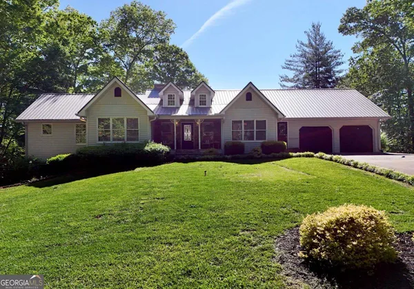 a front view of a house with a garden and trees