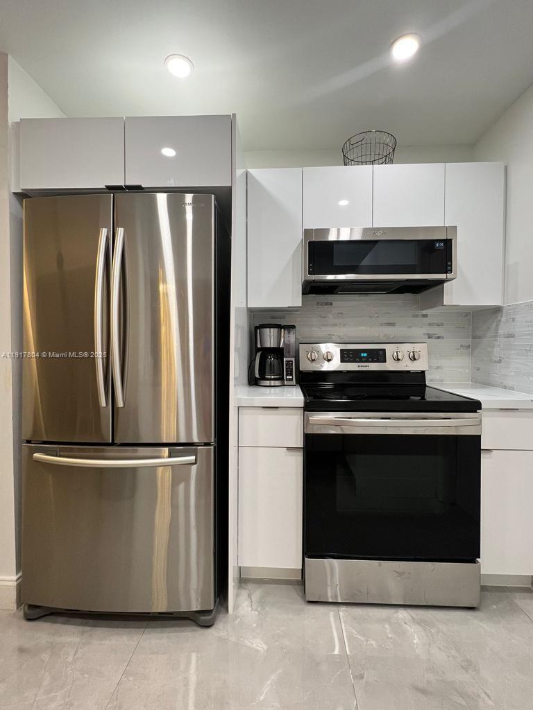 7303 Northwest 57th Drive, Unit 7303 Tamarac, FL 33321 - Photo 3 of 15 a kitchen with stainless steel appliances granite countertop a refrigerator and a stove top oven