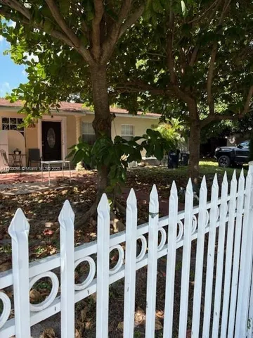 a row of white house with wooden fence and a tree