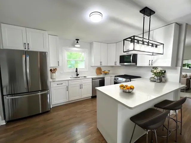 a kitchen with stainless steel appliances a refrigerator a stove a sink dishwasher and white cabinets with wooden floor