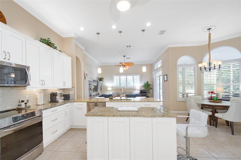 2808 Falcon Ridge Clermont, FL 34711 - Photo 12 of 65 a kitchen with stainless steel appliances kitchen island granite countertop a stove a sink a refrigerator and white cabinets with wooden floor