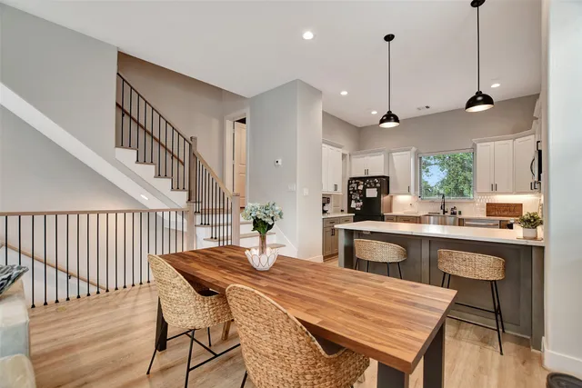 a kitchen with stainless steel appliances kitchen island a dining table chairs and white cabinets