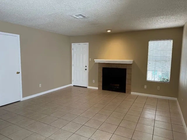 an empty room with windows and fireplace