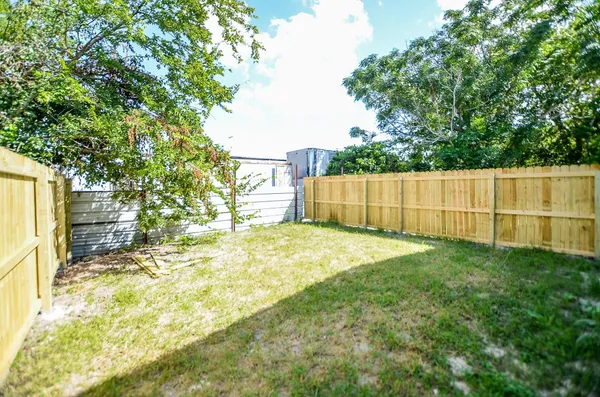 a view of backyard with wooden fence and large trees