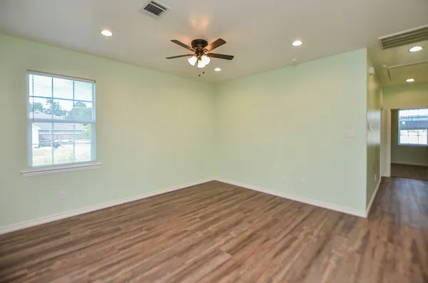 a view of an empty room with wooden floor and a window