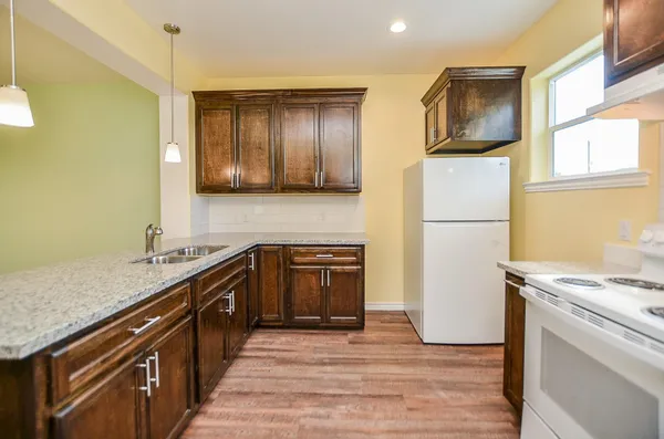 a kitchen with stainless steel appliances granite countertop a refrigerator a stove and a sink with wooden floor