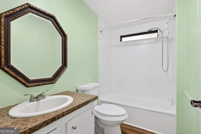 a bathroom with a granite countertop sink toilet and a mirror