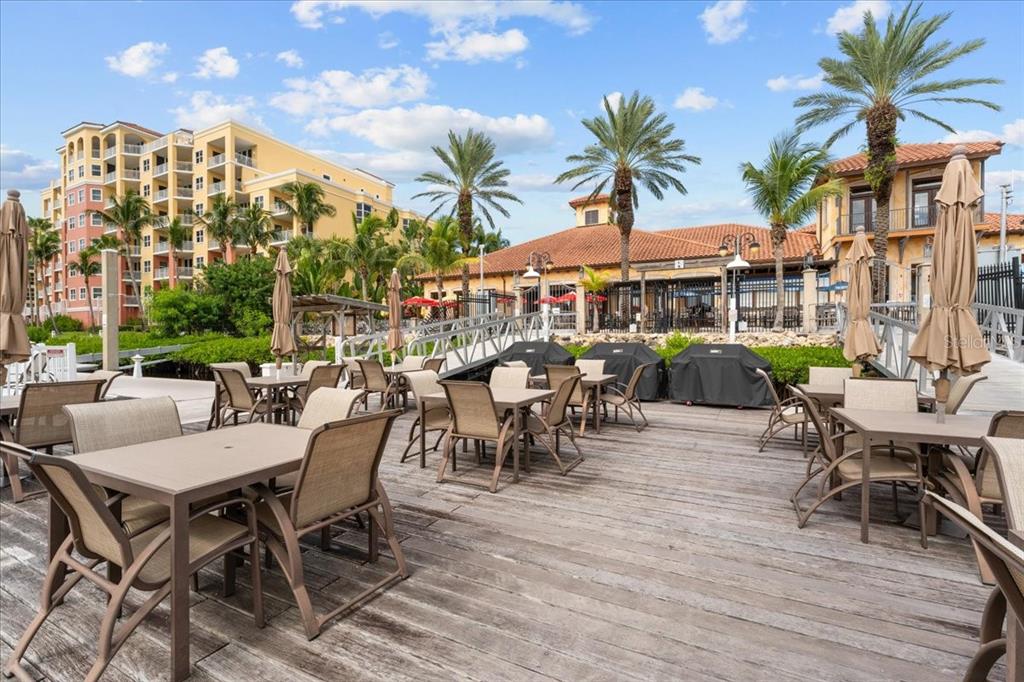 102 Riviera Dunes Way, Unit S39 Palmetto, FL 34221 - Photo 22 of 24 a view of a patio with a dining table and chairs with plants and palm trees