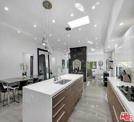 a large kitchen with stainless steel appliances a stove a sink a oven a dining table and chairs