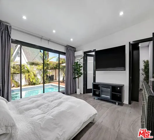 a bedroom with a bed and a flat tv screen next to a large window