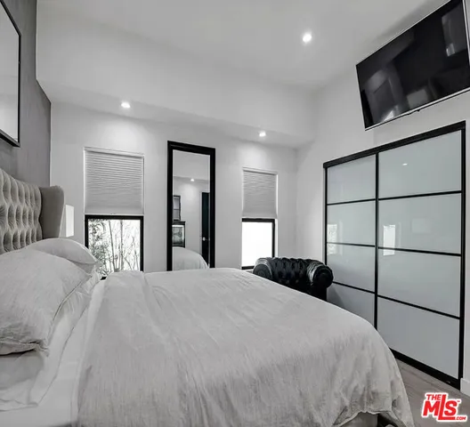 a bedroom with a bed a tv and wooden floor