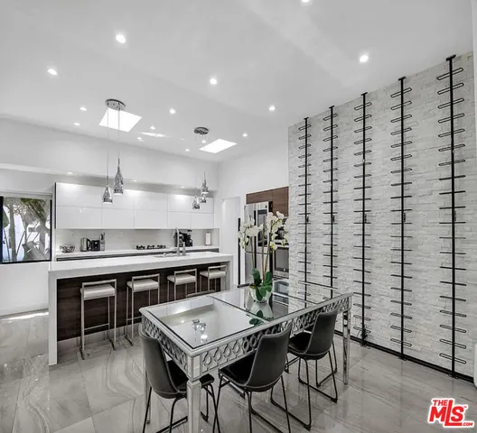 a kitchen with stainless steel appliances kitchen island granite countertop a table chairs sink and stove top oven