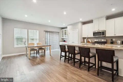 a open dining room with stainless steel appliances wooden floors a table and chairs