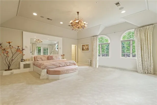 a spacious bedroom with a balcony a bed and a chandelier