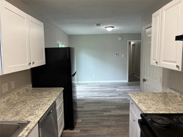 a view of a kitchen with wooden floor and a refrigerator