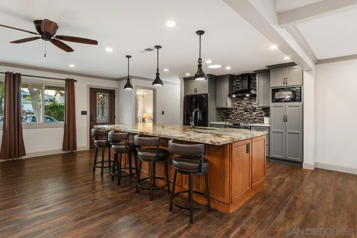 9469 Pike Road Santee, CA 92071 - Photo 6 of 39 a kitchen with stainless steel appliances kitchen island granite countertop a table chairs and a wooden floor