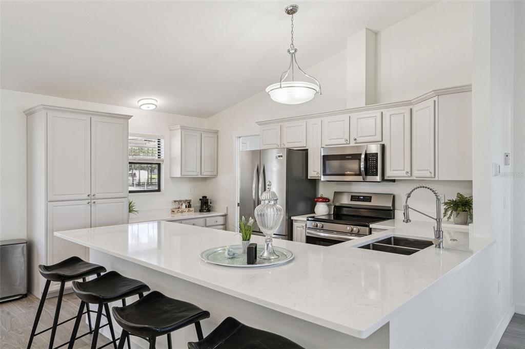 20701 County Road 44A Eustis, FL 32736 - Photo 54 of 73 a kitchen with stainless steel appliances a sink a stove a refrigerator cabinets a dining table and chairs