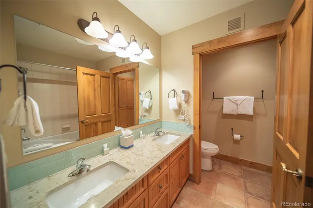 a spacious bathroom with a granite countertop sink a toilet and a mirror
