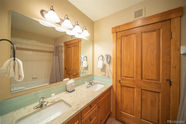 a en suite bathroom with a granite countertop double vanity sink a mirror and a shower