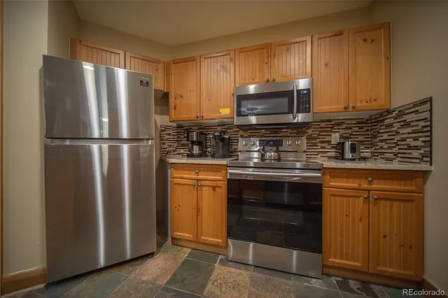 a kitchen with stainless steel appliances granite countertop a refrigerator and a stove top oven