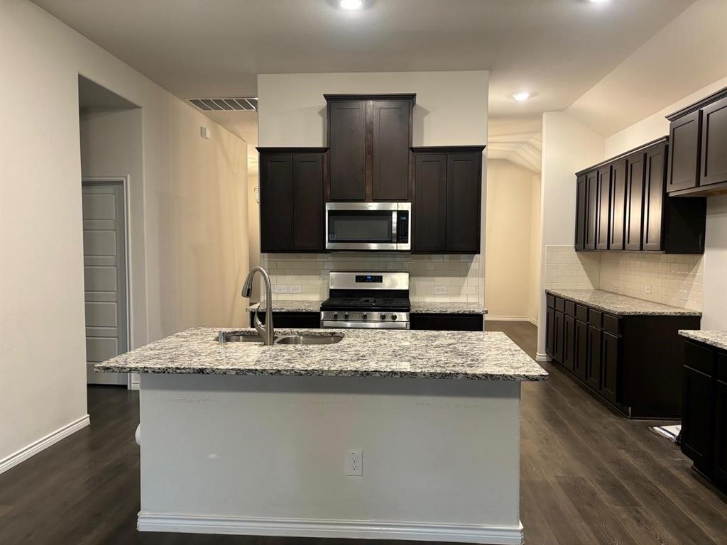 4617 Azurite Road Little Elm, TX 76227 - Photo 3 of 12 a kitchen with stainless steel appliances granite countertop wooden cabinets a refrigerator and a sink