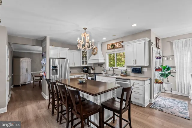 a kitchen with stainless steel appliances a dining table chairs and wooden floor