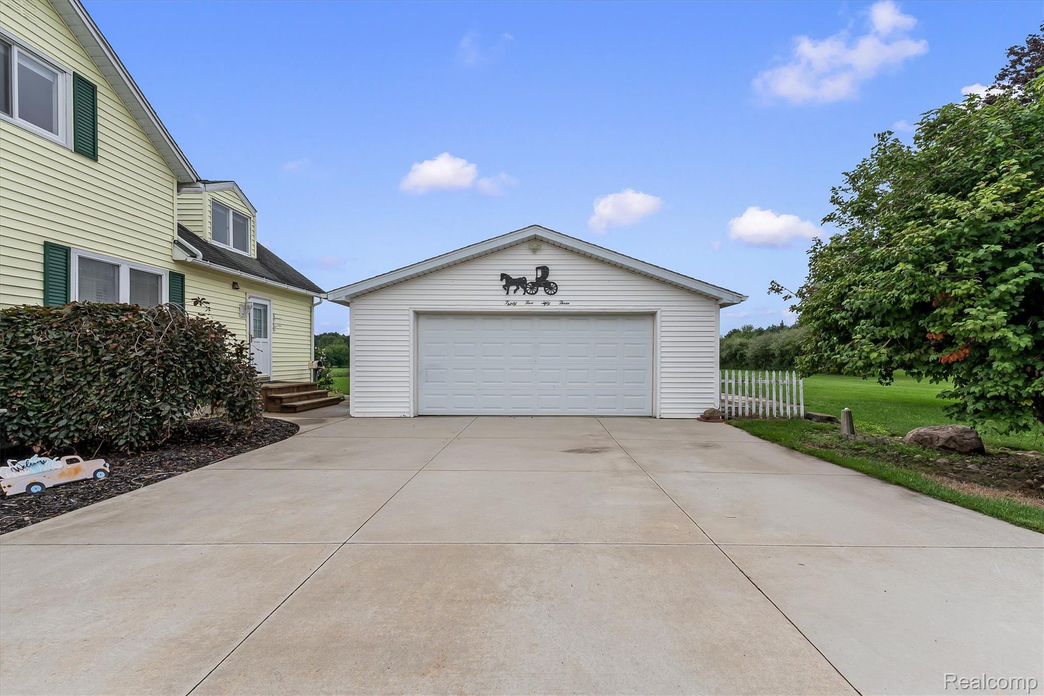 3553 North State Road Owosso, MI 48867 - Photo 5 of 45 Paved driveway leading to a two-car garage with horizontal siding and a white garage door