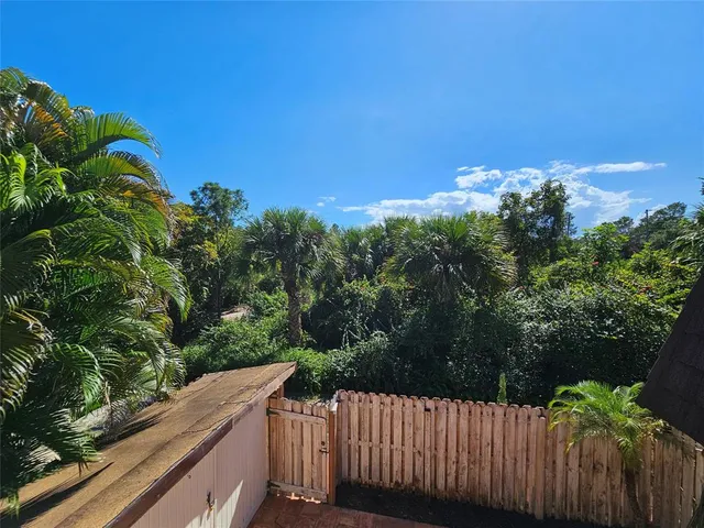 a view of a yard with plants and wooden fence