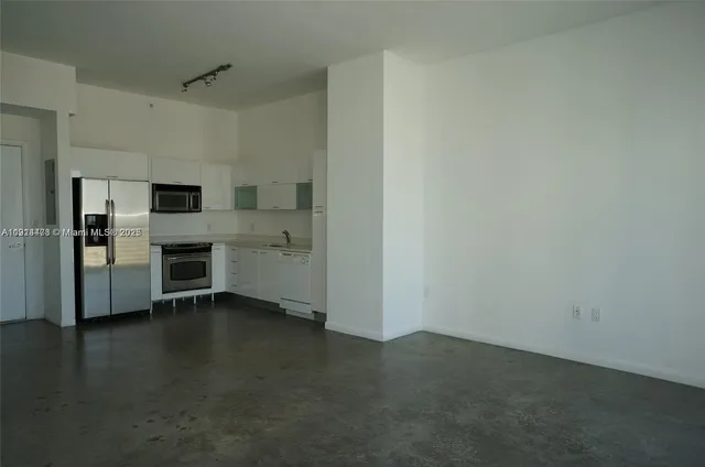 a view of a refrigerator in kitchen and empty room