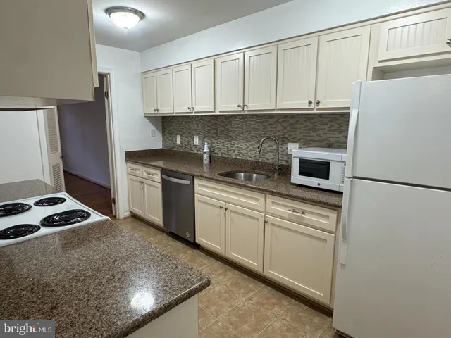 a kitchen with granite countertop a sink stove and refrigerator