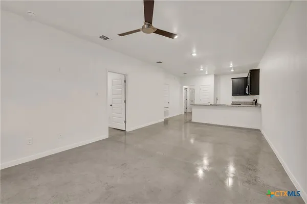 a view of an empty room with kitchen and a window
