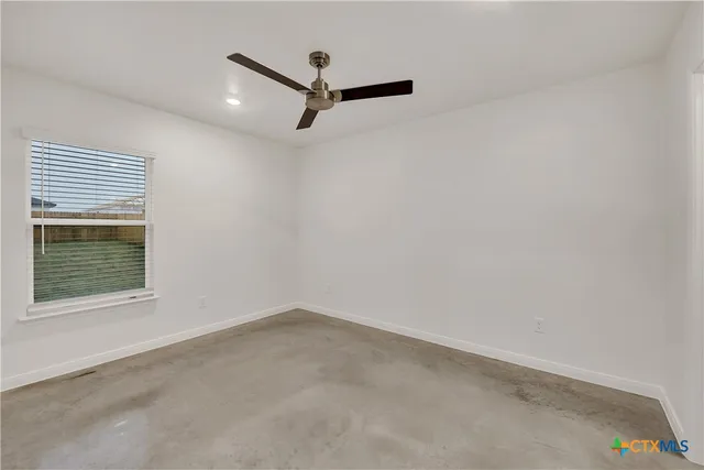 an empty room with a window and a ceiling fan