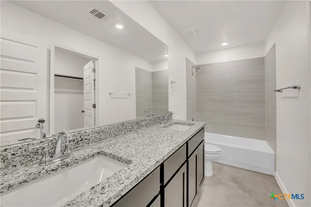 a bathroom with a granite countertop sink a toilet and bathtub