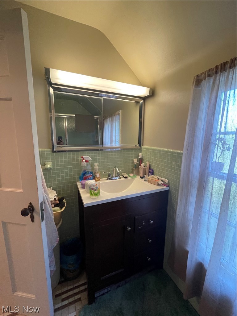 3835 Covington Road Cleveland, OH 44121 - Photo 17 of 34 Bathroom with vanity, tile walls, lofted ceiling, and tasteful backsplash