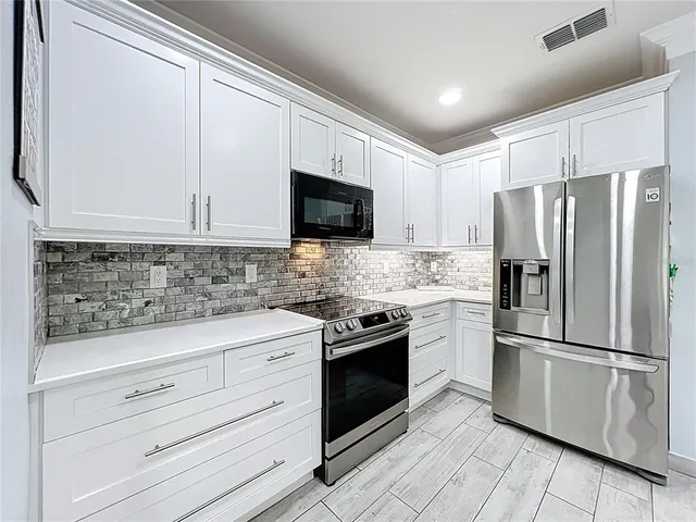 a kitchen with white cabinets stainless steel appliances and a window