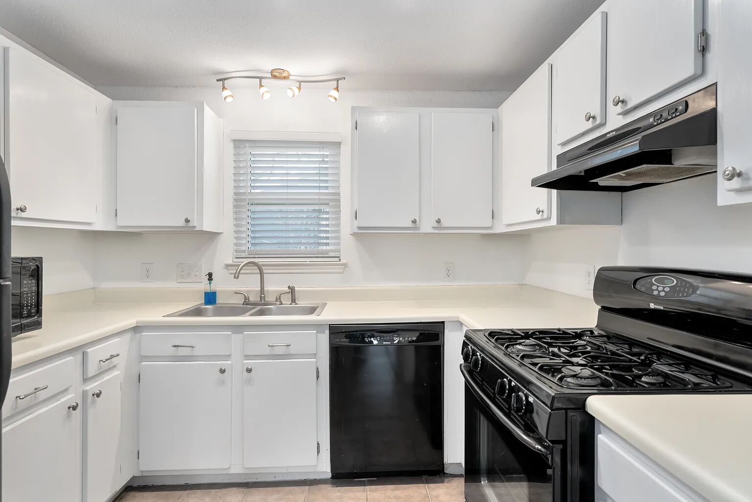 11970 Jollyville Road, Unit 202 Austin, TX 78759 - Photo 7 of 25 A well-appointed kitchen features black appliances, ample counter space, and a sink beneath a large window.
