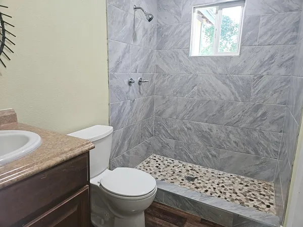 a bathroom with a granite countertop toilet a sink and a shower