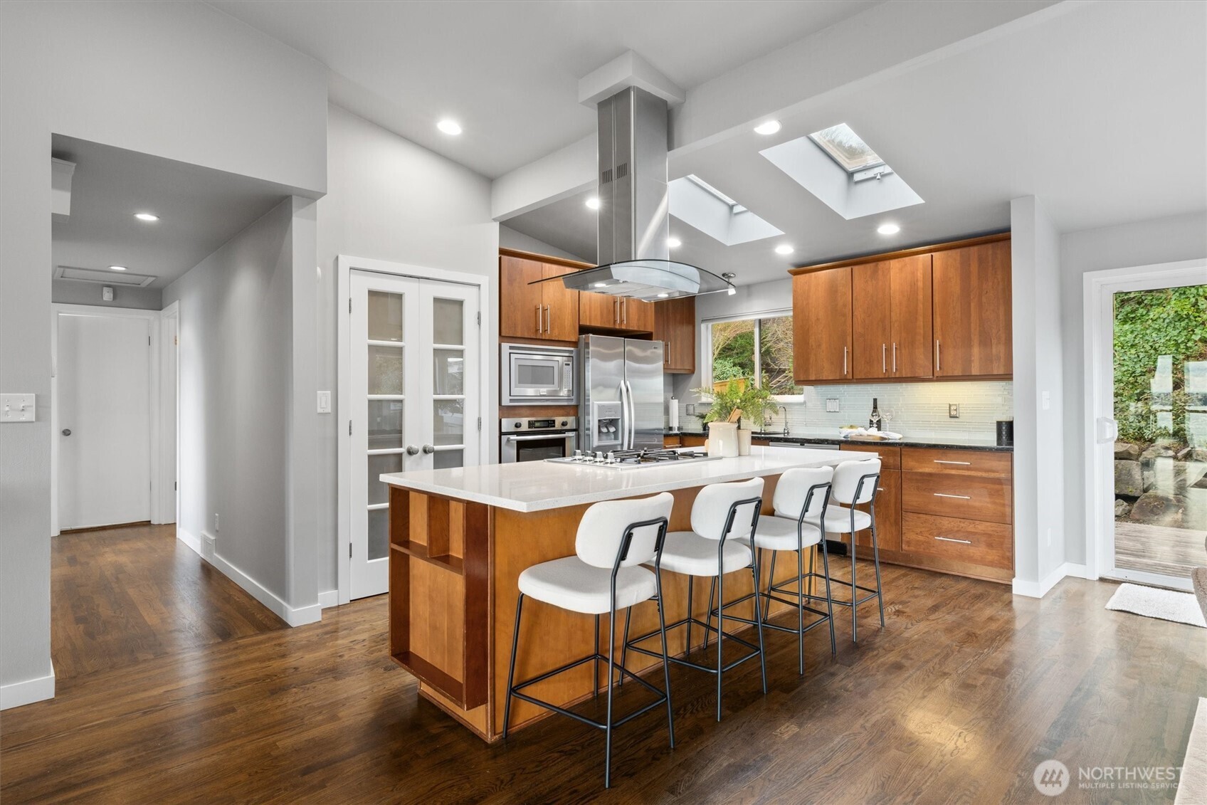8620 Vashon View Southwest Seattle, WA 98136 - Photo 13 of 40 a kitchen with stainless steel appliances kitchen island granite countertop a table chairs cabinets and wooden floor