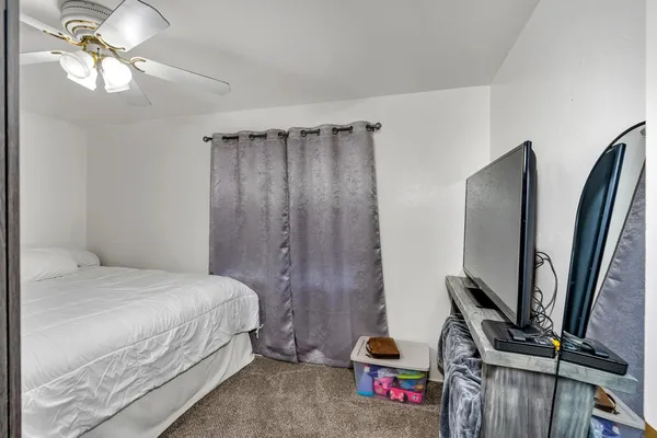 a bedroom with a bed a flat screen tv and a chandelier