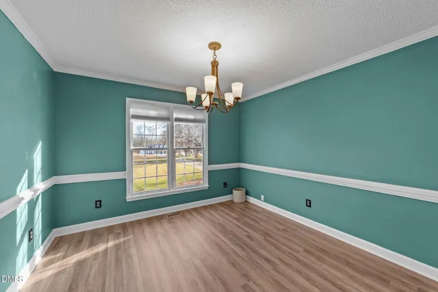 a view of an empty room with wooden floor fireplace and a window