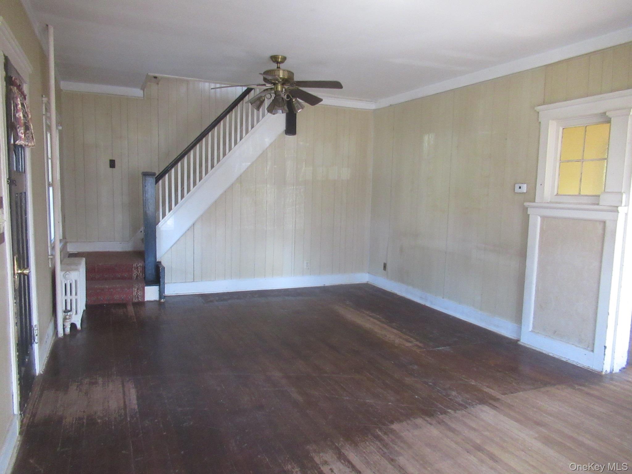 72 Waterstone Road Greenwood Lake, NY 10925 - Photo 11 of 20 Expansive interior space featuring wood-finish flooring, a white-painted staircase with dark handrails, and a ceiling fan