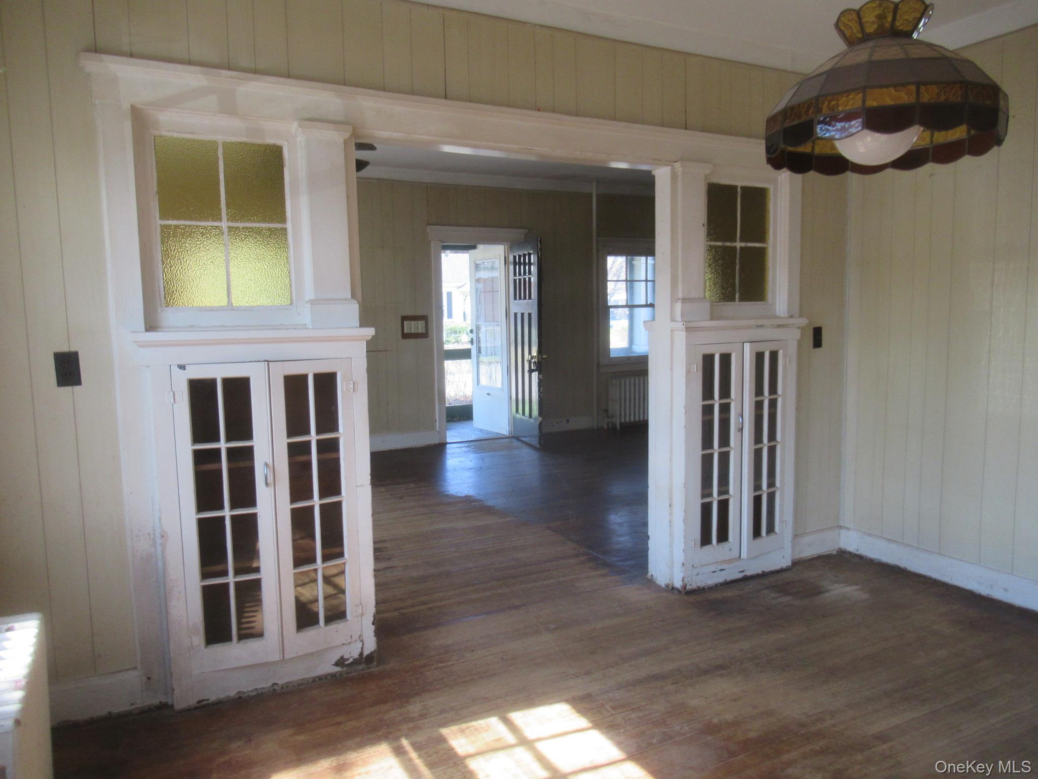 72 Waterstone Road Greenwood Lake, NY 10925 - Photo 8 of 20 Interior room featuring wood-finish flooring, vertical paneling, and an ornate stained-glass light fixture