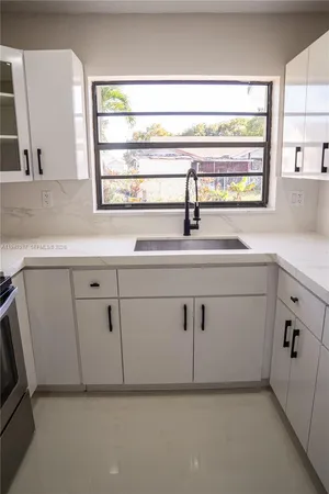 a kitchen with a sink cabinets appliances and a window