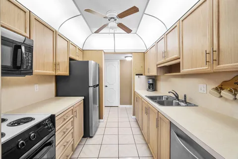 a kitchen with stainless steel appliances a sink a stove a refrigerator cabinets and a dining table