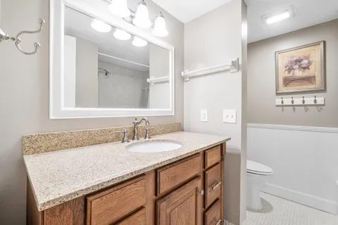 a bathroom with a granite countertop sink a toilet and a mirror
