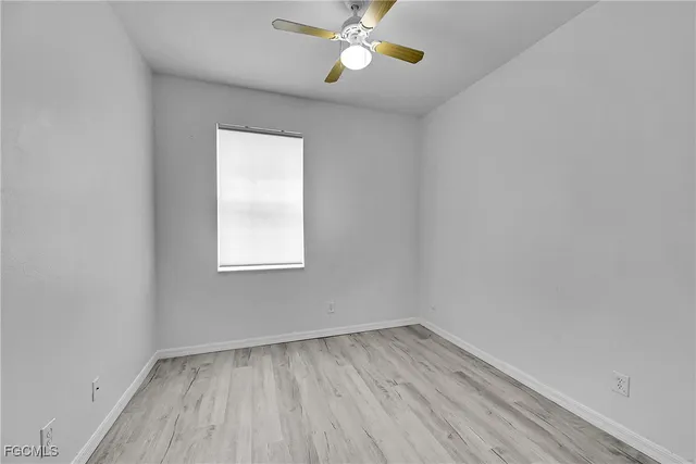an empty room with a window and wooden floor