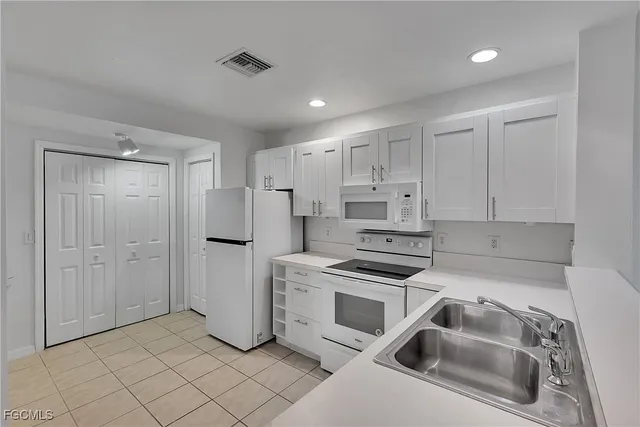 a kitchen that has a sink a refrigerator and cabinets