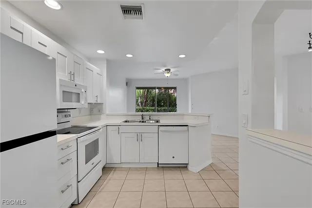 a kitchen with white cabinets and sink